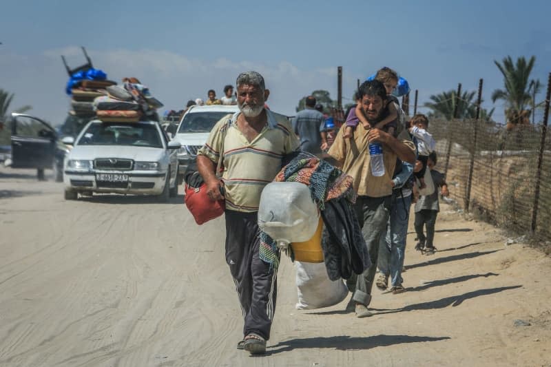 Palestinians carry their belongings as they flee Hamad City towards Al-Mawasi after the Israeli army dropped leaflets demanding that residents of a northern neighborhood in Khan Younis evacuate immediately ahead of a new military operation in the Gaza Strip. Abed Rahim Khatib/dpa