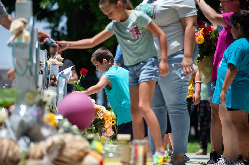 Mourners place flowers, candles and tokens on crosses for each of the Robb Elementary School shooting victims at a memorial put up in the Uvalde Town Square, May 27, 2022.