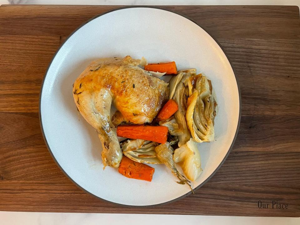 plate of roasted chicken thigh and roasted vegetables on a cutting board