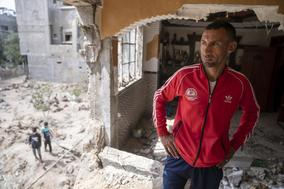 Nader al-Masri, a long-distance runner who participated in dozens of international competitions, including the 2008 Olympics, stands inside his severely damaged home beside the crater where the home of Ramez al-Masri was destroyed by an air-strike prior to a cease-fire reached after an 11-day war between Gaza's Hamas rulers and Israel, Sunday, May 23, 2021, in Beit Hanoun, the northern Gaza Strip. (AP Photo/John Minchillo)