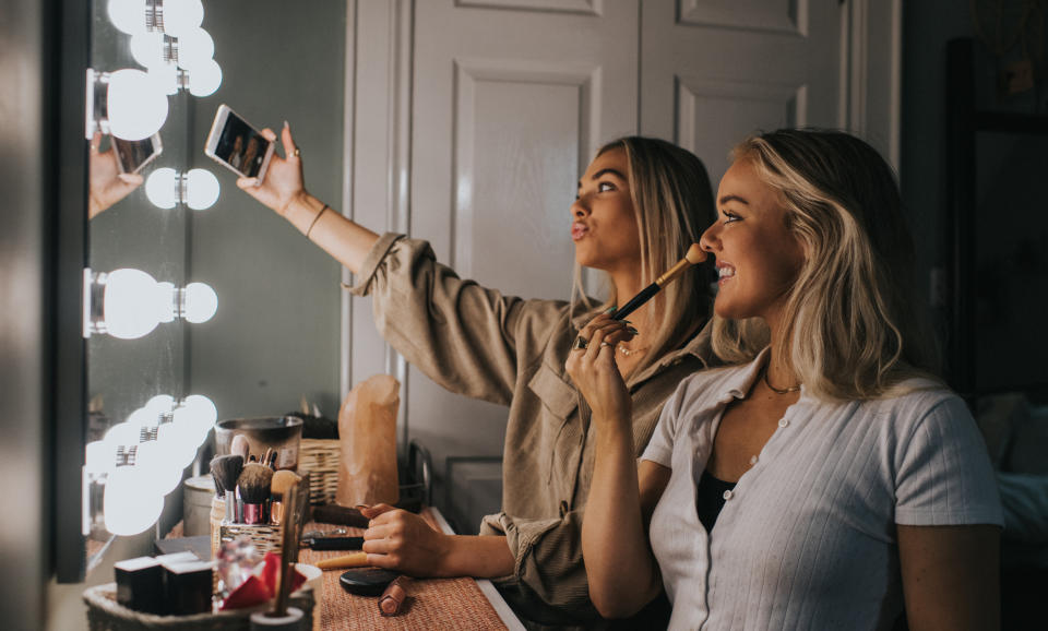 Two women doing makeup and filming