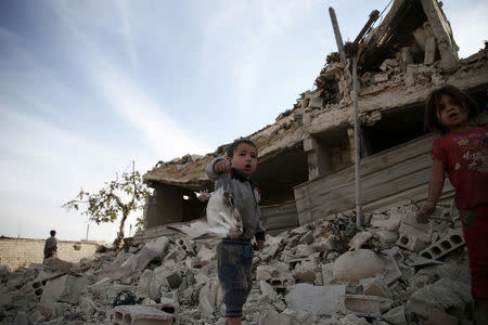 A boy shows a dead pigeon at a site hit previously by an airstrike in the rebel-held Douma neighbourhood of Damascus, Syria October 12, 2016. REUTERS/Bassam Khabieh