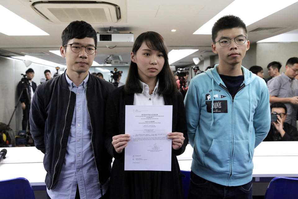 In this Jan. 27, 2018, photo, Agnes Chow, center, a member of democracy Demosisto party, is accompanied by Joshua Wong, right, and Nathan Law, holds a notice from the Hong Kong government at a press conference in Hong Kong. After a security law for Hong Kong passed in China, prominent Hong Kong pro-democracy activists Wong, Chow an Law issued statements on Facebook on Tuesday, June 30, 2020, saying they would withdraw from the pro-democracy organization Demosisto. Wong said "worrying about life and safety" has become a real issue and nobody will be able to predict the repercussions of the law, whether it is being extradited to China or facing long jail terms. (AP Photo/Kin Cheung)