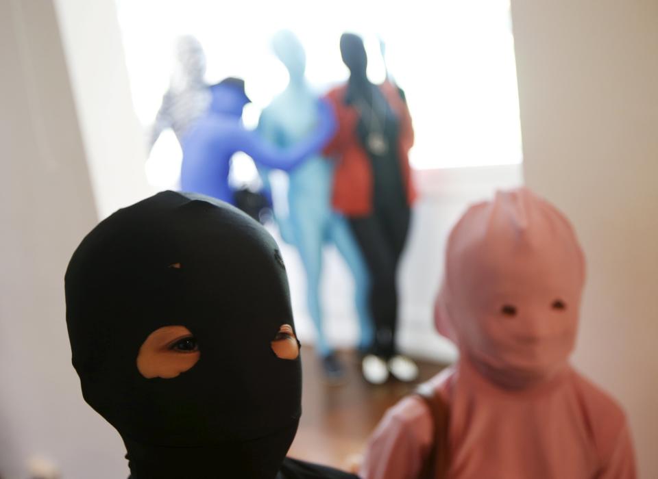 Masaru Morisako poses for photos with another child participant in Zentai costumes before a march down the shopping district of Orchard Road during Zentai Art Festival in Singapore