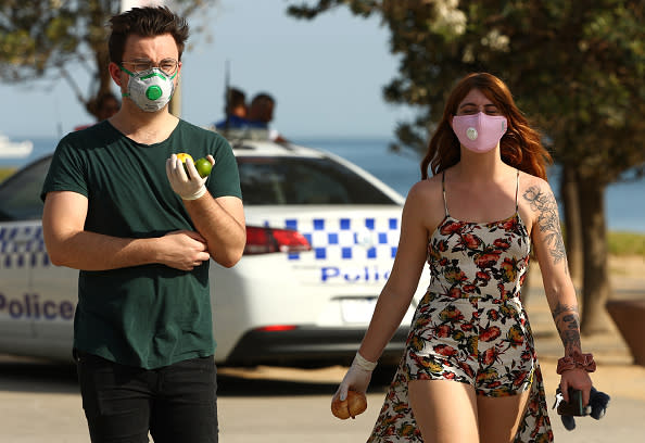 People are seen at St Kilda Beach in Melbourne wearing face masks.