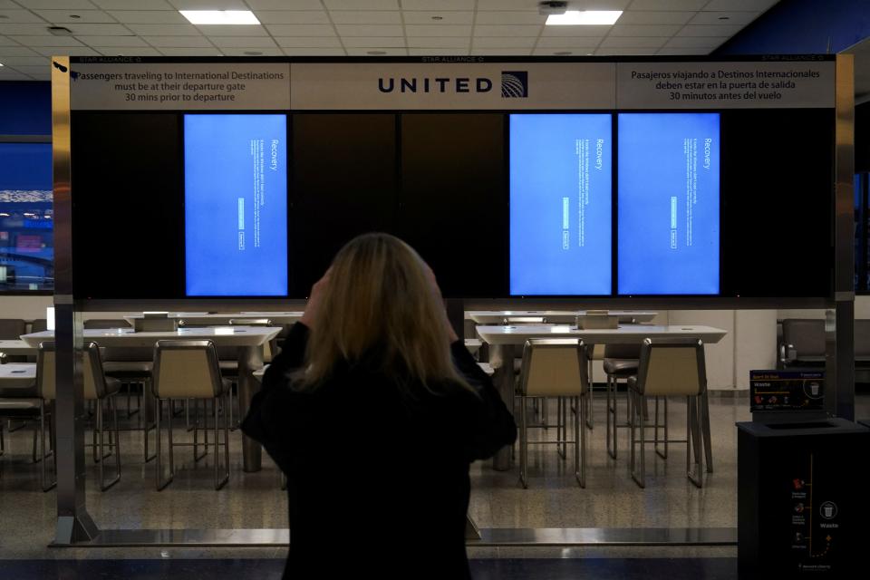 A traveler uses her mobile phone to photograph a departures board displaying blue error screens, also known as the u0022Blue Screen of Deathu0022 inside Terminal C in Newark International Airport, after United Airlines and other airlines grounded flights due to a worldwide tech outage caused by an update to CrowdStrike's u0022Falcon Sensoru0022 software which crashed Microsoft Windows systems, in Newark, New Jersey, U.S., July 19, 2024. Bing Guan, Reuters