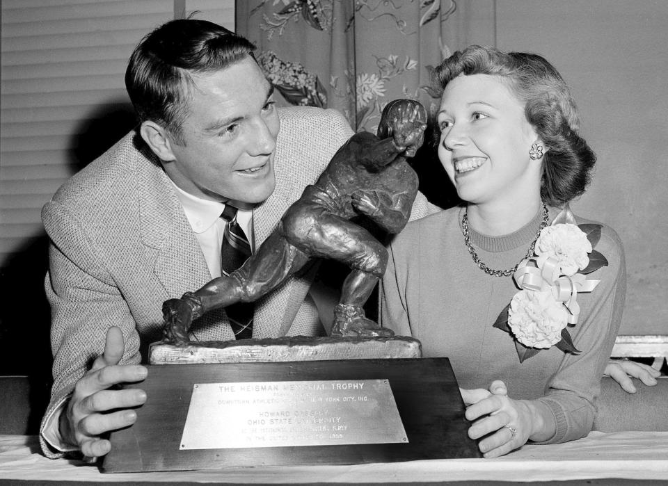 In this Dec. 8, 1955, file photo, All-America Howard "Hopalong" Cassady, halfback for Ohio State, and his wife, Barbara, pose with the Heisman Trophy awarded to Cassady in New York. Cassady, a Heisman Trophy winner and former NFL running back, died early Friday, Sept. 20, 2019, in Tampa, Fla., Jerry Emig, the Ohio State associate athletic director said. He was 85. Cassady played both football and baseball at Ohio State in the early 1950s, winning the Heisman Trophy in 1955. He also played 10 seasons in the NFL, mostly with the Detroit, and got the nickname "Hopalong" from local sports writers after the black-hatted Western star of the 1950s. (AP Photo)