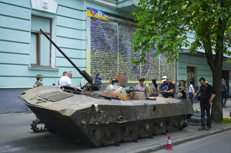 People look at a Russian military vehicle destroyed by the Ukrainian troops in a battle against the Russian invaders and taken to the capital as a reminder of war in Kyiv, Ukraine, Thursday, May 12, 2022.(AP Photo/Efrem Lukatsky)