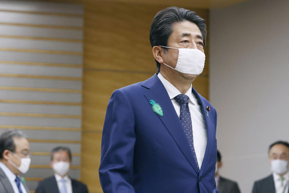 Japanese Prime Minister Shinzo Abe wearing a face mask walks to attend a video conference with executives of Japan's private companies at his official residence in Tokyo Thursday, April 16, 2020. Abe is considering expanding an ongoing state of emergency to all of Japan from just Tokyo and other urban areas as the virus continued to spread. (Kyodo News via AP)