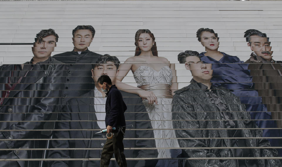 A man wearing a face mask as a precaution against the coronavirus, walks past in front of an advertisement of an opera performance outside of a theater in Seoul, South Korea, Wednesday, March 3, 2021. (AP Photo/Lee Jin-man)