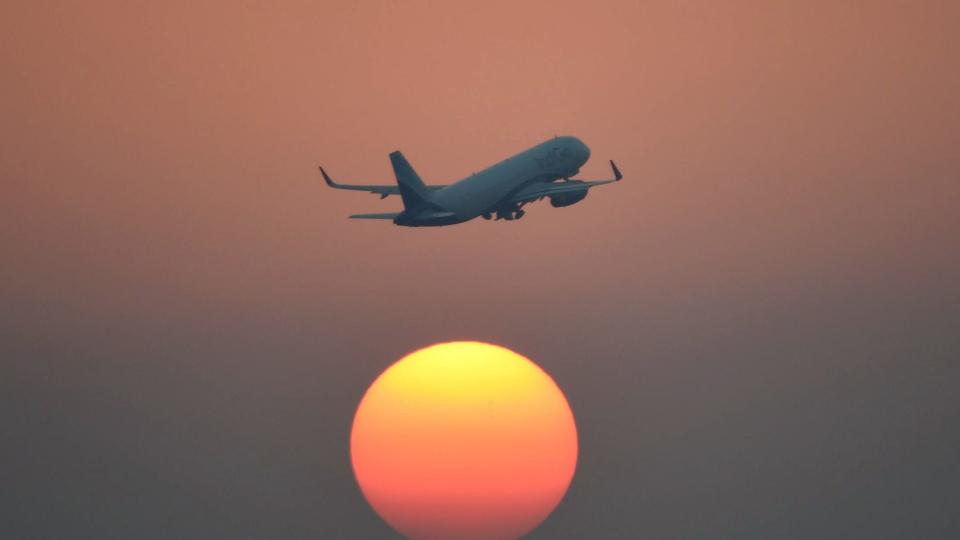 An airliner of India's IndiGo carrier flies over the setting sun in New Delhi