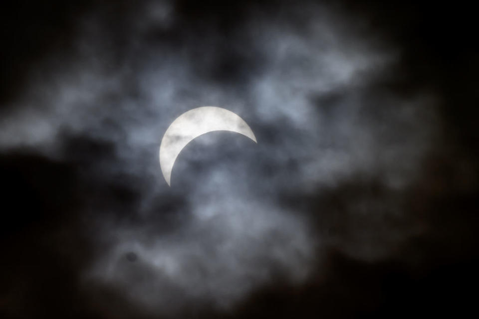 A view of the partial solar eclipse behind the clouds as seen from the Syracuse University quad on April 8, 2024 in Syracuse, New York.  Millions of people have flocked to areas of North America that are in the 