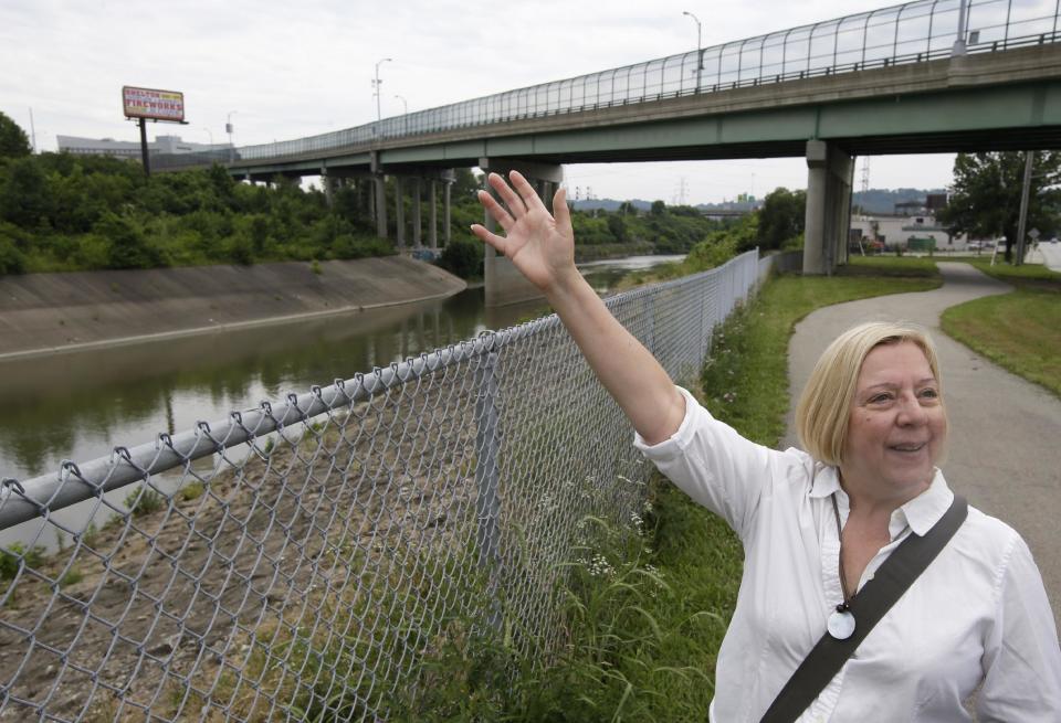 In this Wednesday, June 12, 2013 photo, Robin Corathers, executive director of Groundwork Cincinnati, stands next to the Mill Creek, in Cincinnati. The creek runs through industrial areas and has long been a problem due to deforestation, pollution and sewer overflow. The city of Cincinnati is growing an edible forest garden near the creek as part of a years-long effort to restore the Mill Creek valley. (AP Photo/Al Behrman)