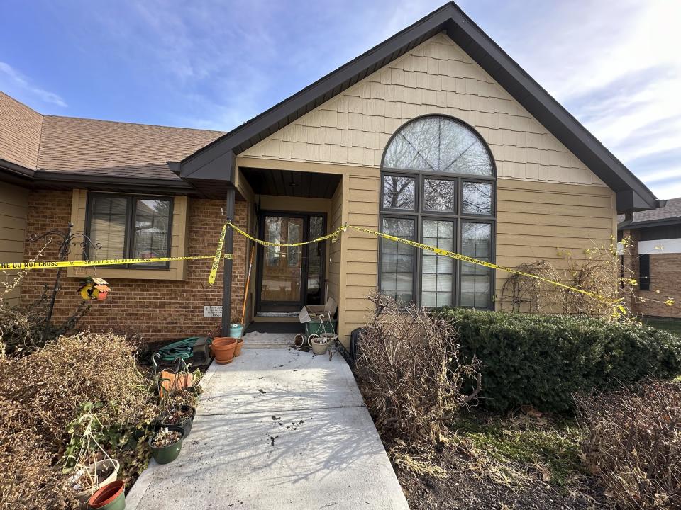 The front door of the rectory where the Rev. Stephen Gutgsell's was fatally stabbed on Dec. 10 in tiny Fort Calhoun, Neb., remained wrapped in crime scene tape on Thursday, Dec. 14, 2023. A cornerstone next to the door the suspect broke into identifies the home as being the one St. John the Baptist Catholic Church's priest lived at. Gutgsell's killing was the second one in the small town in the last four months. (AP Photo/Josh Funk)
