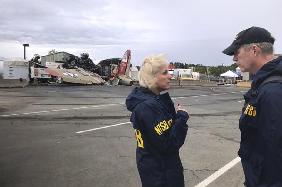 In this photo released via Twitter by the National Transportation Safety Board, NTSB board Member Jennifer Homendy, left, and investigator Dan Bower stand at the scene where a World War II-era bomber plane, left, crashed at Bradley International Airport in Windsor Locks, Conn., Wednesday, Oct. 2, 2019. (National Transportation Safety Board via AP)