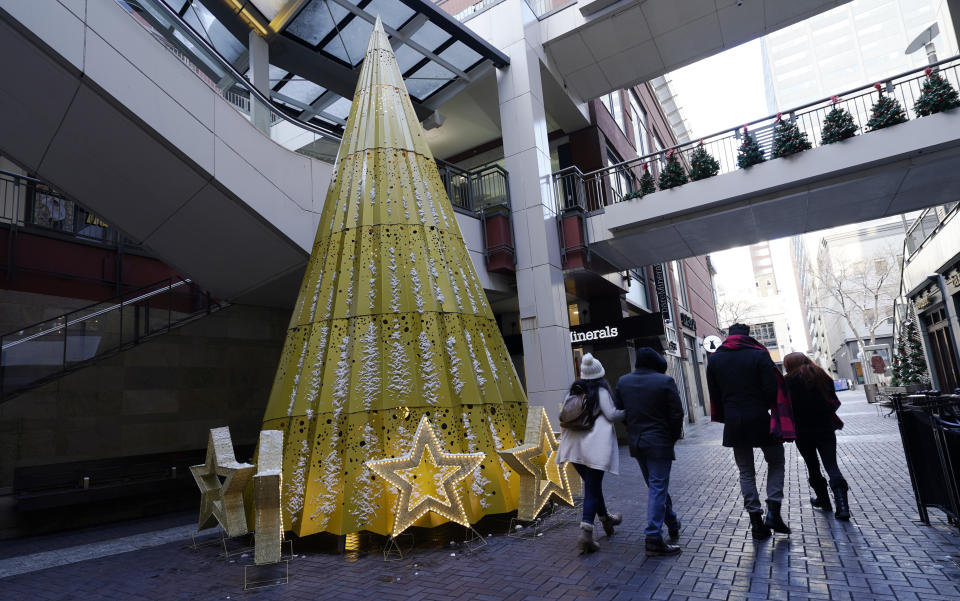 Shoppers wear face masks while in search of after-Christmas bargains in shops in the Denver Pavilions Tuesday, Dec. 29, 2020, in downtown Denver. (AP Photo/David Zalubowski)