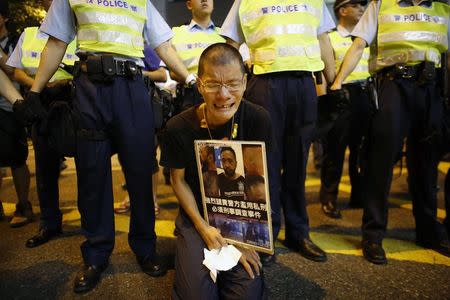 A pro-democracy protester cries as he holds a placard with photos of Ken Tsang Kin-chiu, a hospitalized protester, during a rally in front of the police headquarters of Wan Chai district in Hong Kong in this October 15, 2014 file photo. REUTERS/Carlos Barria/Files