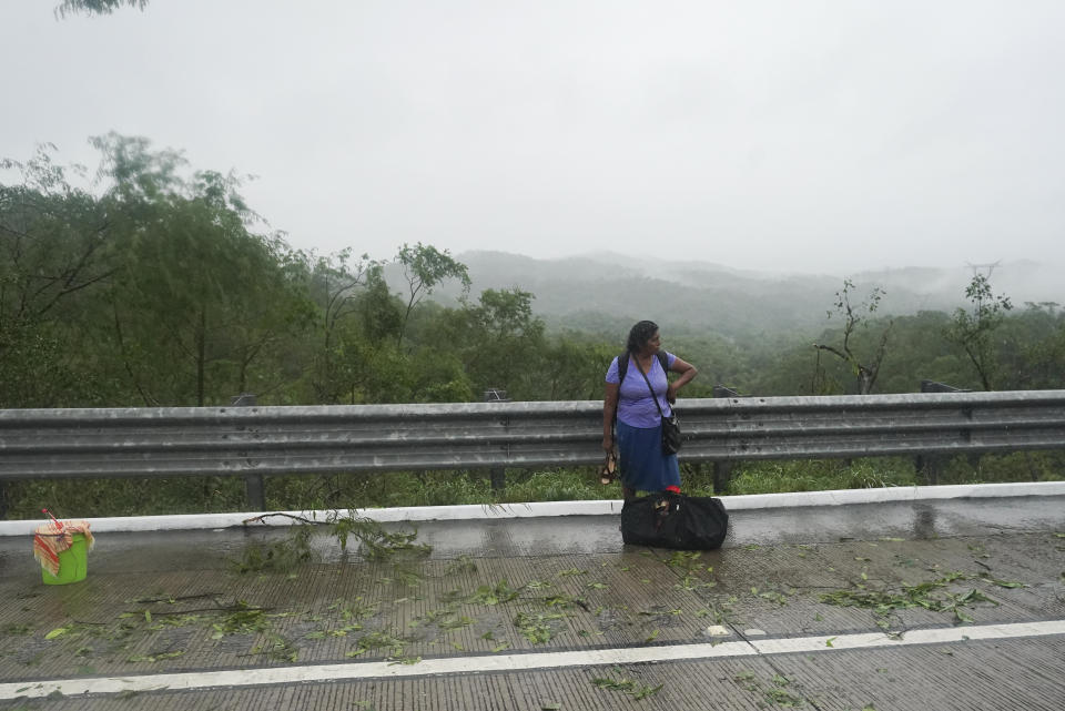 A commuter who got off a bus stands idle on a highway blocked by a landslide triggered by Hurricane Otis near Acapulco, Mexico, Wednesday, Oct. 25, 2023. (AP Photo/Marco Ugarte)