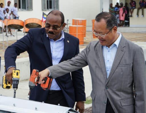 Antigua and Barbuda's Prime Minister Gaston Browne (L) and China's Ambassador to the country, Wang Xianmin, lay a ceremonial nail in Codrington, Barbuda on July 12, 2018