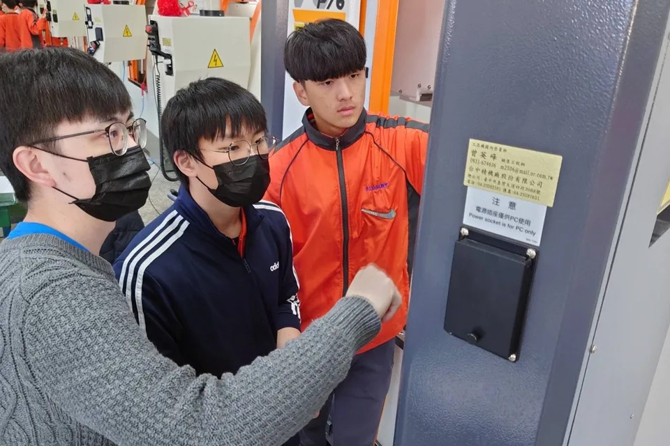國手教師賴右餘（左）指導學生操作CNC加工機