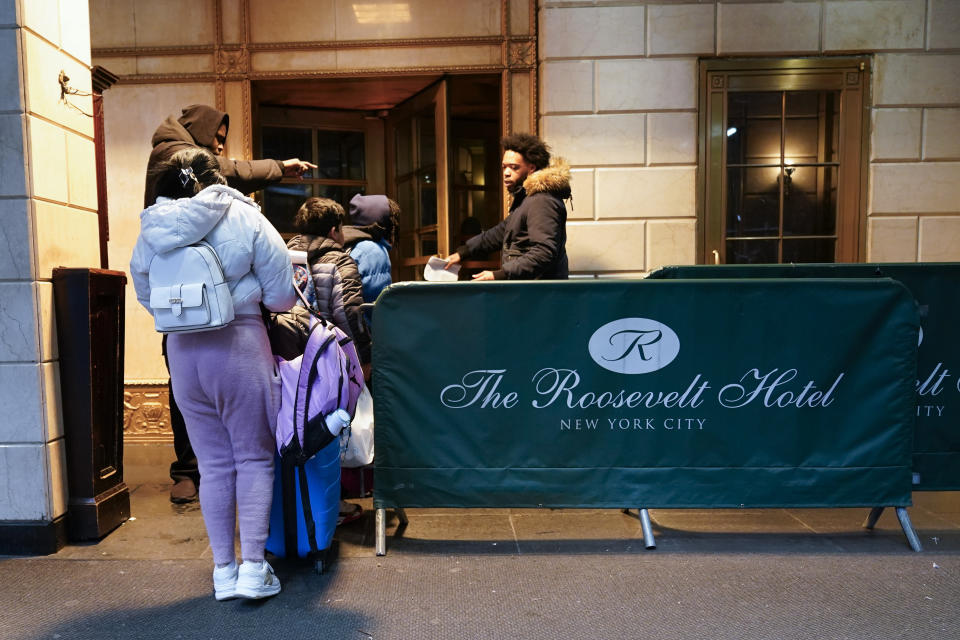 Security guards at the Roosevelt Hotel allow an immigrant family to enter, Tuesday, Jan. 9, 2024, in New York. (AP Photo/Mary Altaffer)