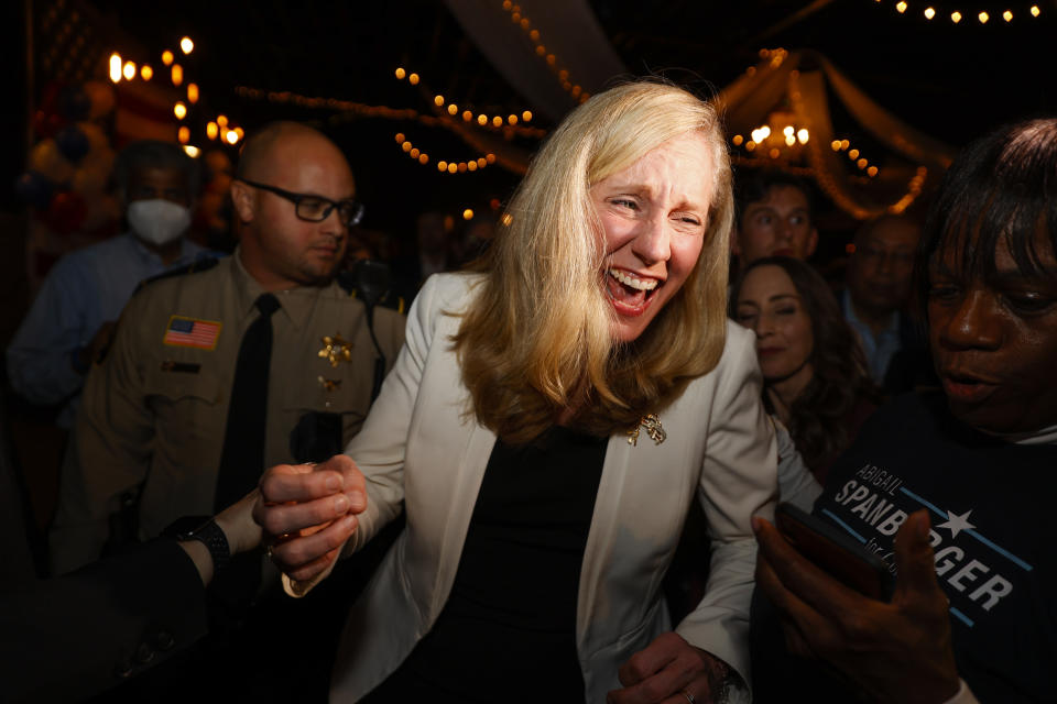 Rep. Abigail Spanberger looking jubilant with supporters in a room strung with strings of lights.
