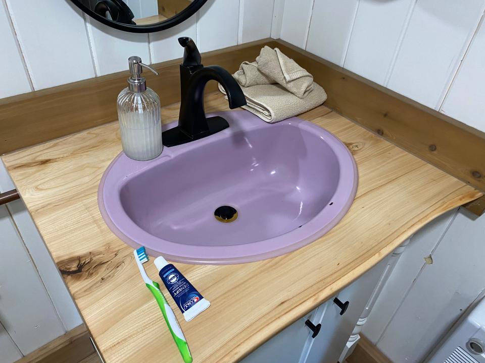 purple sink with toothbrush and toothpaste next to it