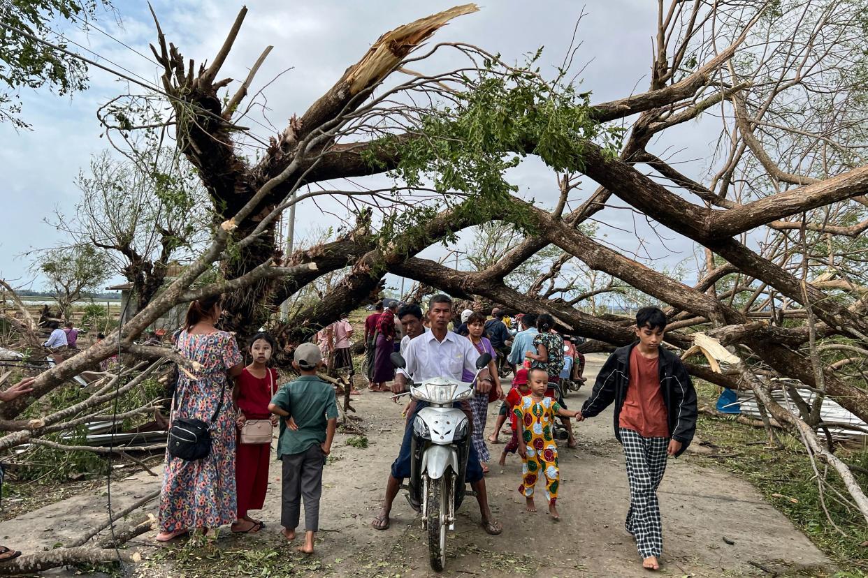 Residents walk past fallen trees in Kyauktaw, Myanmar, on Monday, a day after Cyclone Mocha made landfall. (Sai Aung Main/AFP via Getty Images)