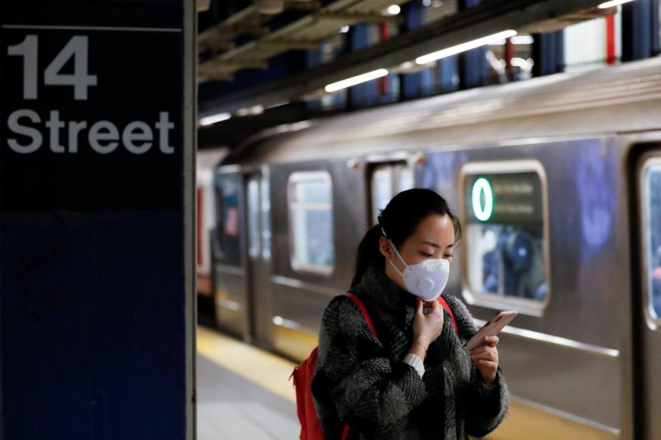 A woman wears a face mask as she waits on the subway (REUTERS)