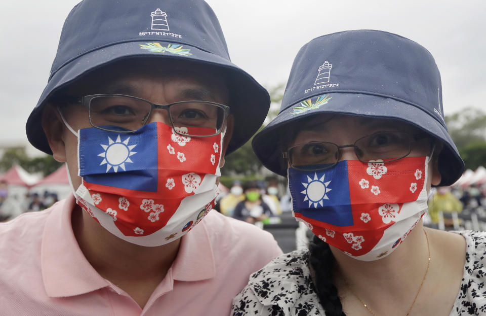 People wear masks patterned with Taiwan national flags during National Day celebrations in front of the Presidential Building in Taipei, Taiwan, Monday, Oct. 10, 2022. (AP Photo/Chiang Ying-ying)