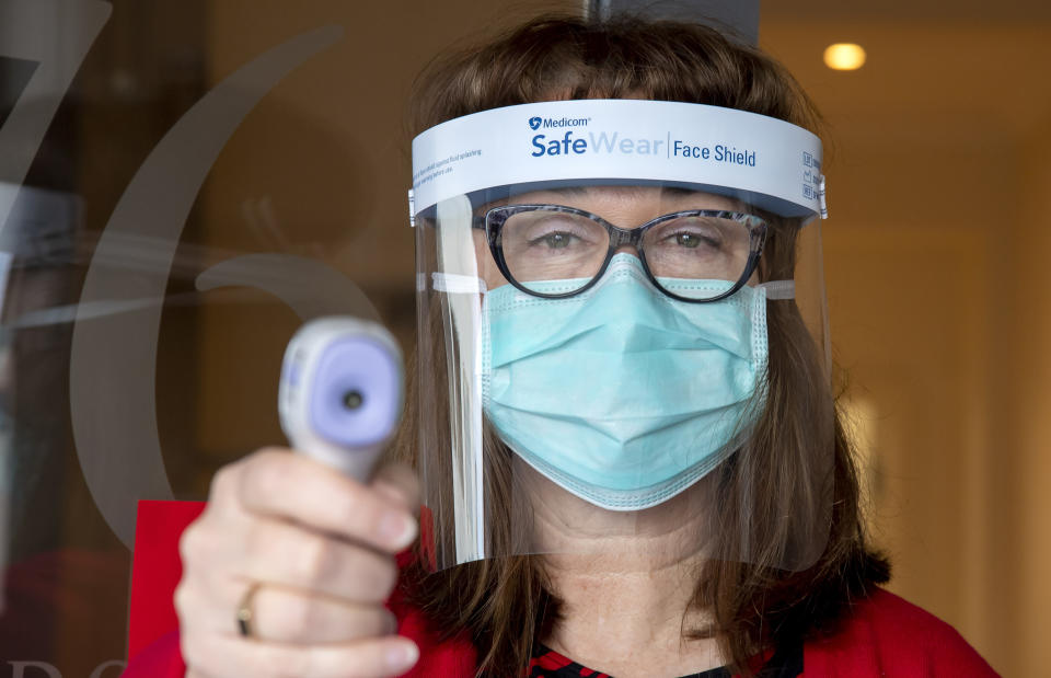 A medical staff checks the temperature of a patient during lockdown due to the continuing spread of the coronavirus in Melbourne, Thursday, Aug. 6, 2020. Victoria state, Australia's coronavirus hot spot, announced on Monday that businesses will be closed and scaled down in a bid to curb the spread of the virus. (AP Photo/Andy Brownbill)