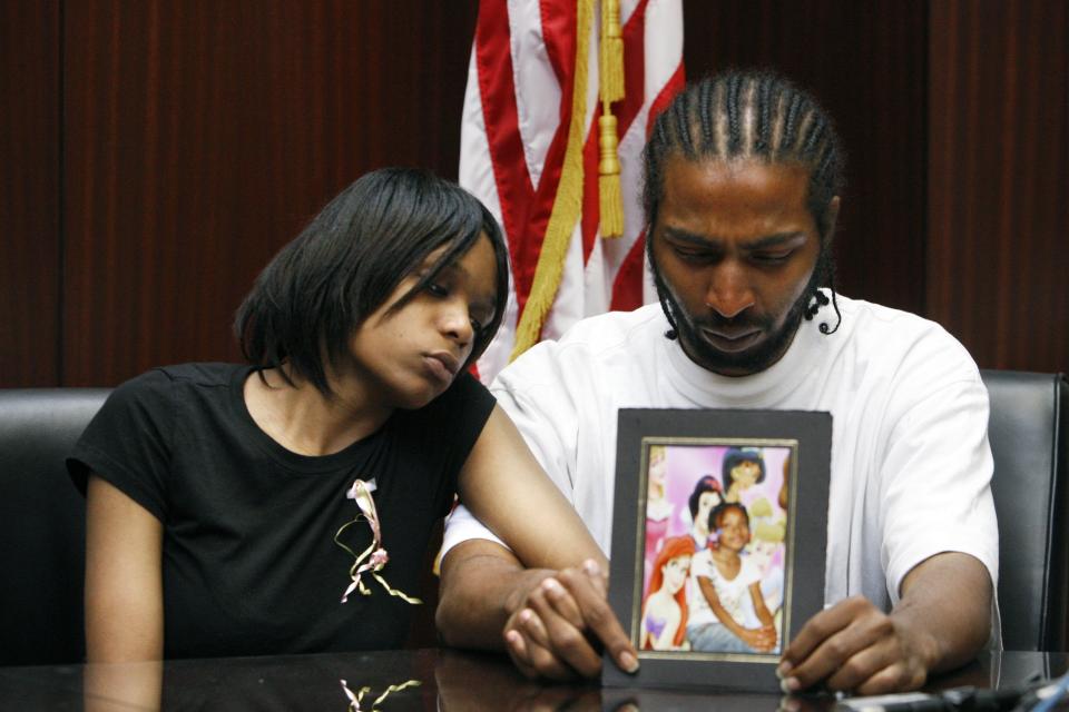 FILE - In this May 18, 2010 file photo, Dominika Stanley, left, the mother of 7-year-old Aiyana Stanley-Jones, sits next to Aiyana's father Charles Jones, who holds a photo of her in Southfield, Mich. The family sued the city and was awarded more than $8 million after she was shot to death during a 2010 police raid at her home while sleeping on a sofa. (AP Photo/Carlos Osorio, File)