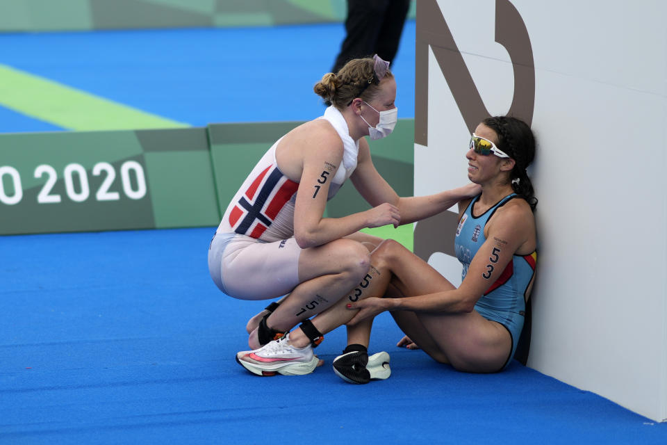 FILE - Claire Michel, of Belgium, is assisted by Lotte Miller of Norway after the finish of the women's individual triathlon competition at the 2020 Summer Olympics, in Tokyo, Japan, July 27, 2021. Belgium's Olympic committee announced Sunday Aug.4, 2024 that it would withdraw its team from the mixed relay triathlon at the Paris Olympics after one of its competitors who swam in the Seine River fell ill. Claire Michel, who competed in the women's triathlon Wednesday, "is unfortunately ill and will have to withdraw from the competition," the Belgian Olympic and Interfederal Committee said in a statement. (AP Photo/David Goldman, File)