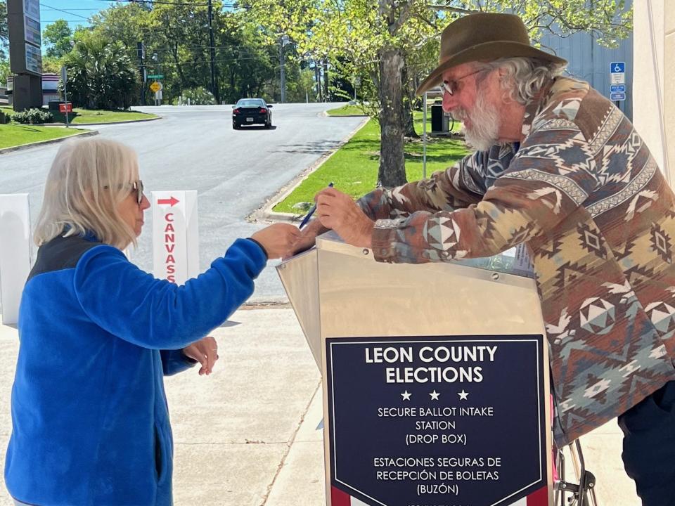 Robert Feuerstein helps a voter with their ballot at a drop off box March 19, 2024