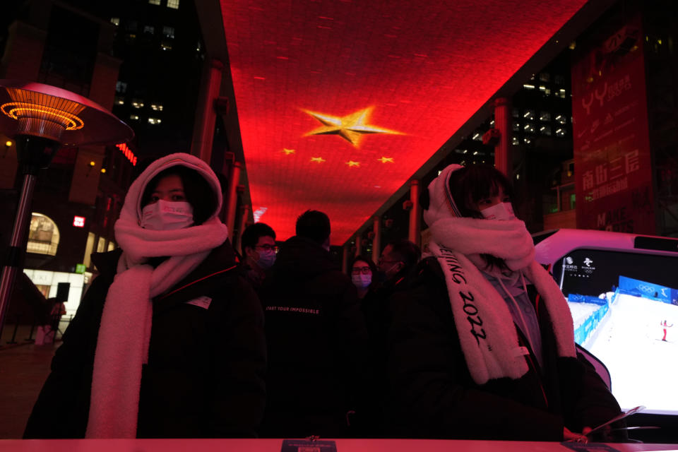 Promoters at an event organized by sponsors of the 2022 Winter Olympics wait for visitors at a mall in Beijing on Thursday, Feb. 10, 2022. The possibility of a large outbreak in the bubble, potentially sidelining athletes from competitions, has been a greater fear than any leakage into the rest of China. (AP Photo/Ng Han Guan)