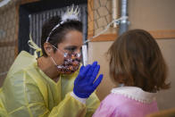 Medical personnel hands over a non-invasive Covid 19 test with chewing gum to a child at the G.B. Grassi school, in Fiumicino, near Rome, Tuesday, Oct. 6, 2020. (AP Photo/Andrew Medichini)