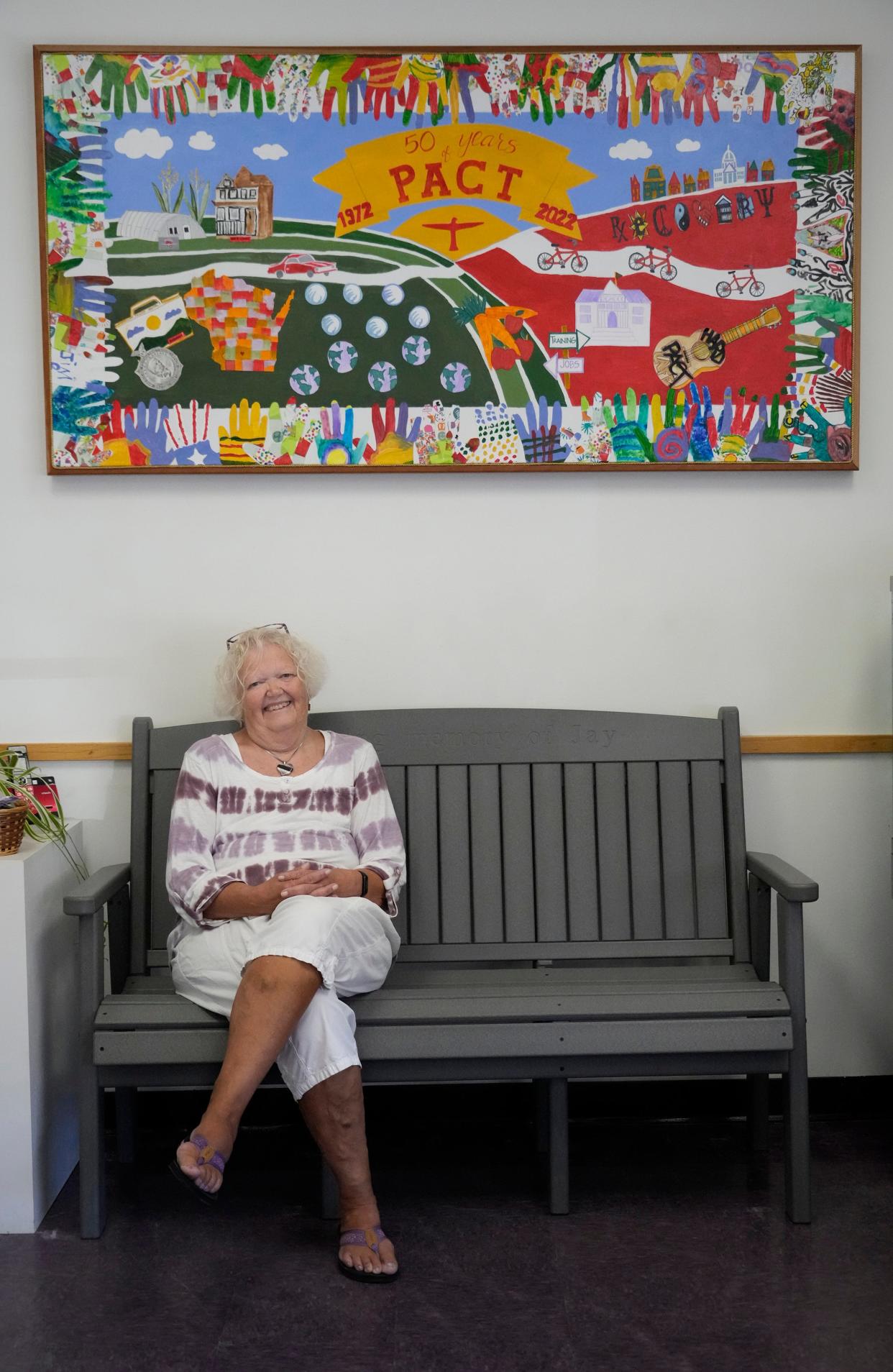 Jana Frey, director of the Program of Assertive Community Treatment, sits below a mural that was created in 2022 for its 50th anniversary.