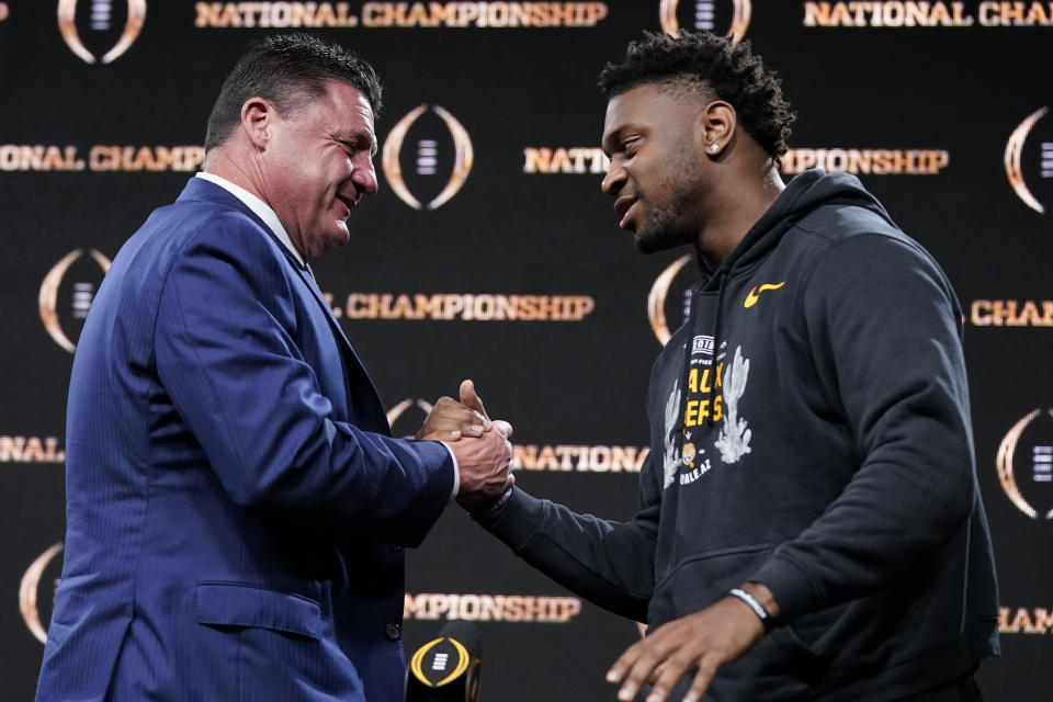 LSU head coach Ed Orgeron, left, greets linebacker Patrick Queen after a news conference for the NCAA College Football Playoff national championship game Tuesday, Jan. 14, 2020, in New Orleans. LSU won 42-25 over Clemson on Monday. (AP Photo/David J. Phillip)