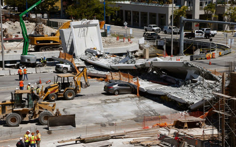 Crushed cars lie under a section of a collapsed pedestrian bridge near Florida International University - Credit: AP