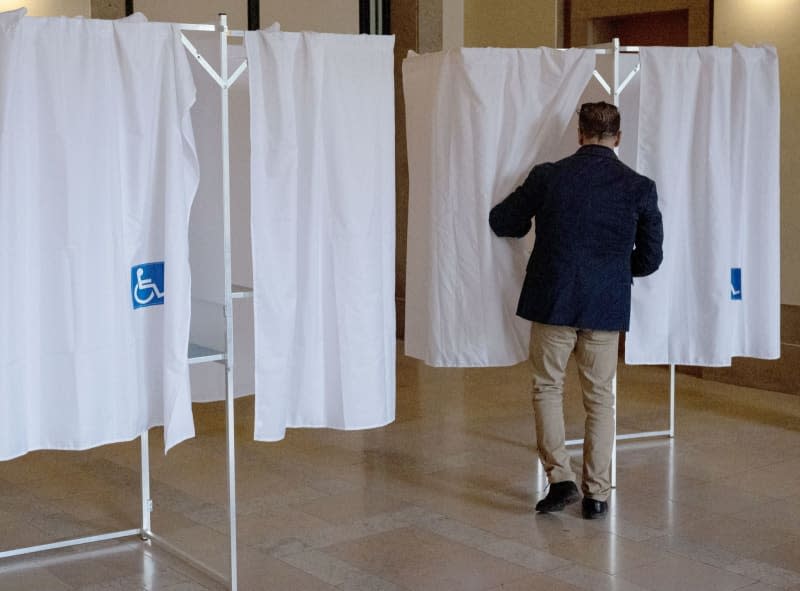 A man enters a booth to cast his vote at a polling station during the second round of the French parliamentary elections. On July 7, 2024, France is holding parliamentary elections that will be decisive for the country's political future and in which the far right could become the largest party in parliament for the first time. Hannes P. Albert/dpa