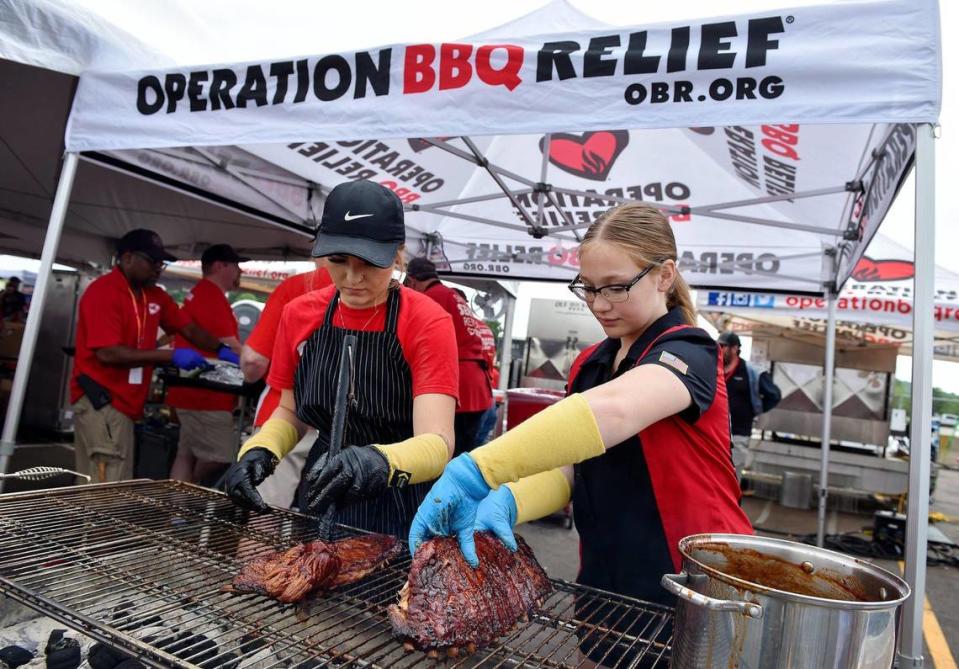 Samantha Mulford of Ottawa bastes and Anna Hays of Pleasant Hill turns ribs as they caramelize the ribs over the fire Sunday at the Kansas City BBQ Festival at the GEHA Field at Arrowhead Stadium.. Mulford and Hays are volunteers with Operation BBQ Relief, a non-profit that feeds first responders and people affected during a disaster and also provides hunger relief to communities with food insecurity. The three-day festival concluded Sunday.