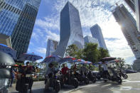 Men on electric bikes wait for riders near the Evergrande headquarters, center, in Shenzhen, China, Friday, Sept. 24, 2021. Seeking to dispel fears of financial turmoil, some Chinese banks are disclosing what they are owed by a real estate developer that is struggling under $310 billion in debt, saying they can cope with a potential default. (AP Photo/Ng Han Guan)