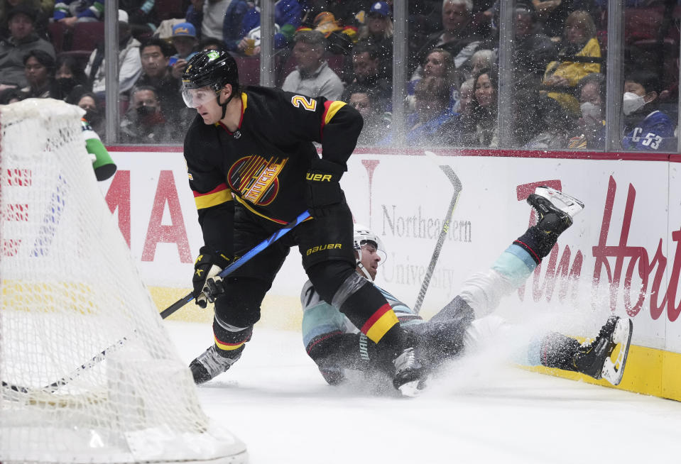 Seattle Kraken's Joonas Donskoi crashes into the boards behind Vancouver Canucks' Luke Schenn during the third period of an NHL hockey game Tuesday, April 26, 2022, in Vancouver, British Columbia. (Darryl Dyck/The Canadian Press via AP)