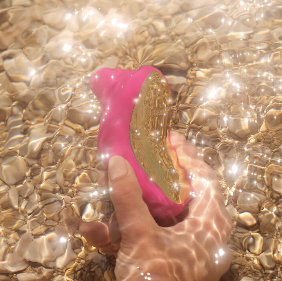 Sona Cruise pink vibrator in hand under water (Photo via Lelo)