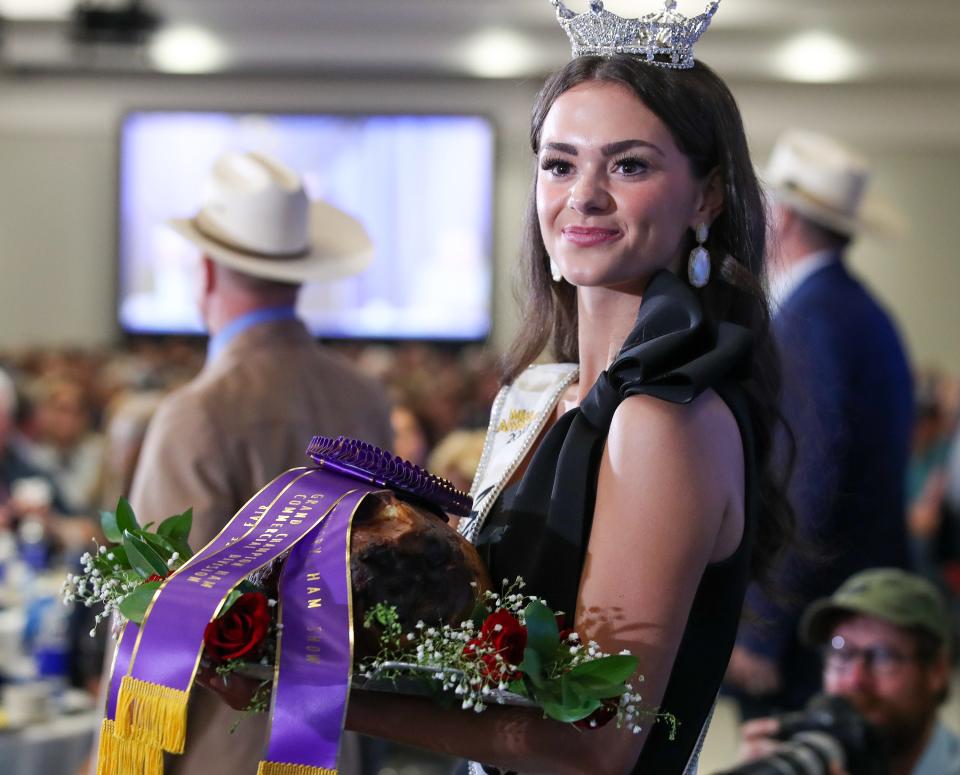 Miss Kentucky, Mallory Hudson of Bowling Green, holds the grand champion ham during the auction during the annual Kentucky Farm Bureau Country Ham Breakfast.  Joe and Kelly Craft, along with Central Bank, made joint $5 million bids for the 18-pound grand champion ham making it a record $10 million for charity.