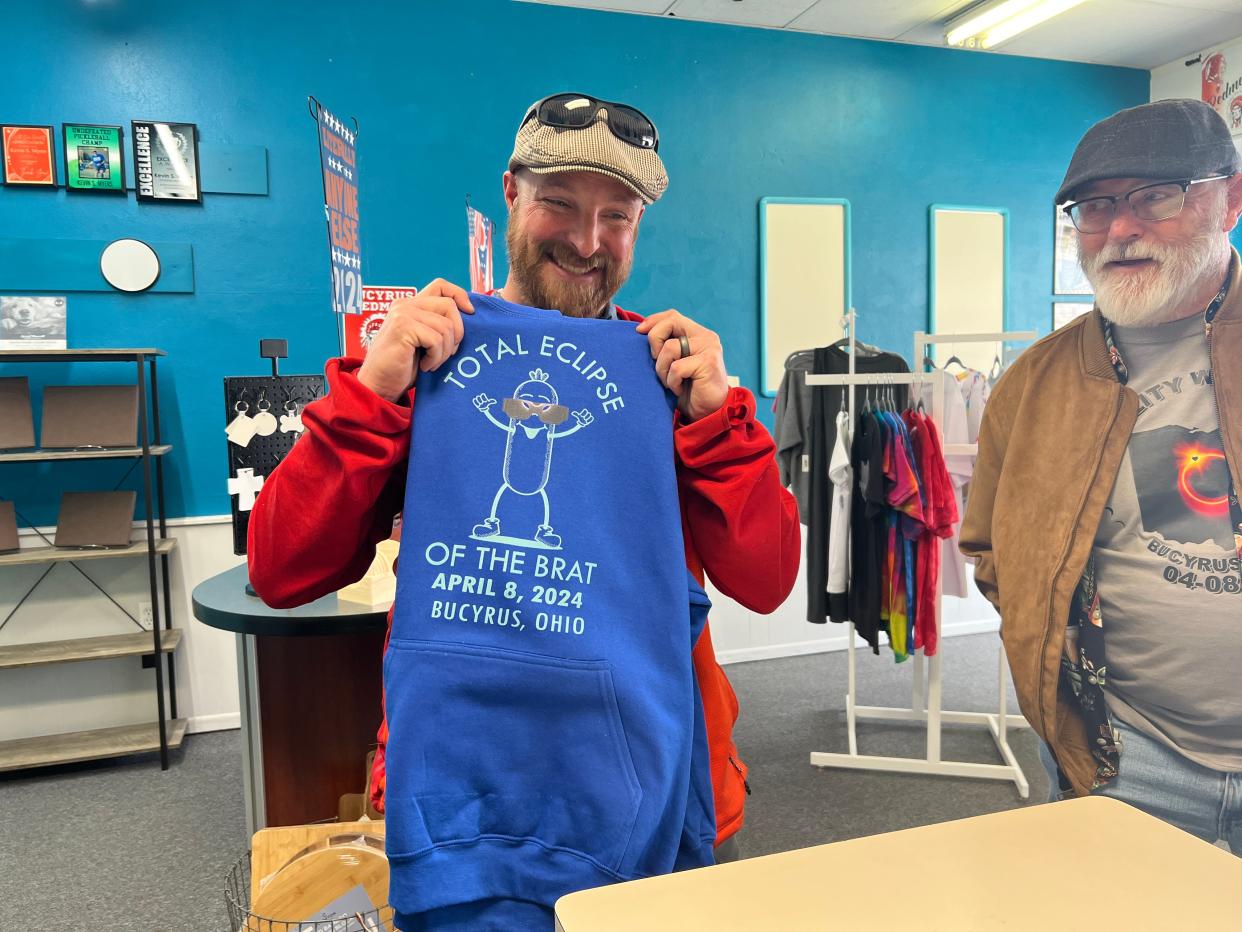 Jeremy West of Colorado and his father, Larry West of Bucyrus, check out the eclipse-themed sweatshirt created by the team at Print Happier last week. (KIMBERLY GASURAS FOR TELEGRAPH-FORUM)