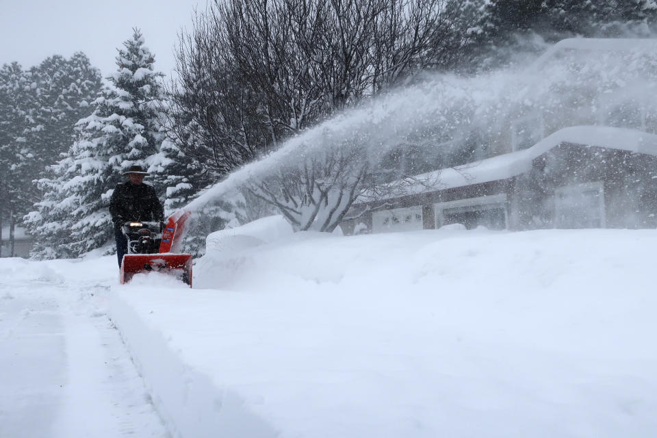 Richard Henn runs a snow blower down the sidewalk outside his home in Flagstaff, Arizona, on Thursday, Feb. 21, 2019. Schools across northern Arizona canceled classes and some government offices decided to close amid a winter storm that's expected to dump heavy snow in the region. (AP Photo/Felicia Fonseca)