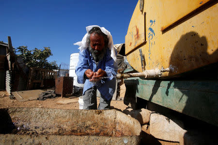 A Palestinian man washes his face from a water tank near his house on the outskirts of the West Bank village of Yatta, south of Hebron, August 17, 2016. REUTERS/Mussa Qawasma