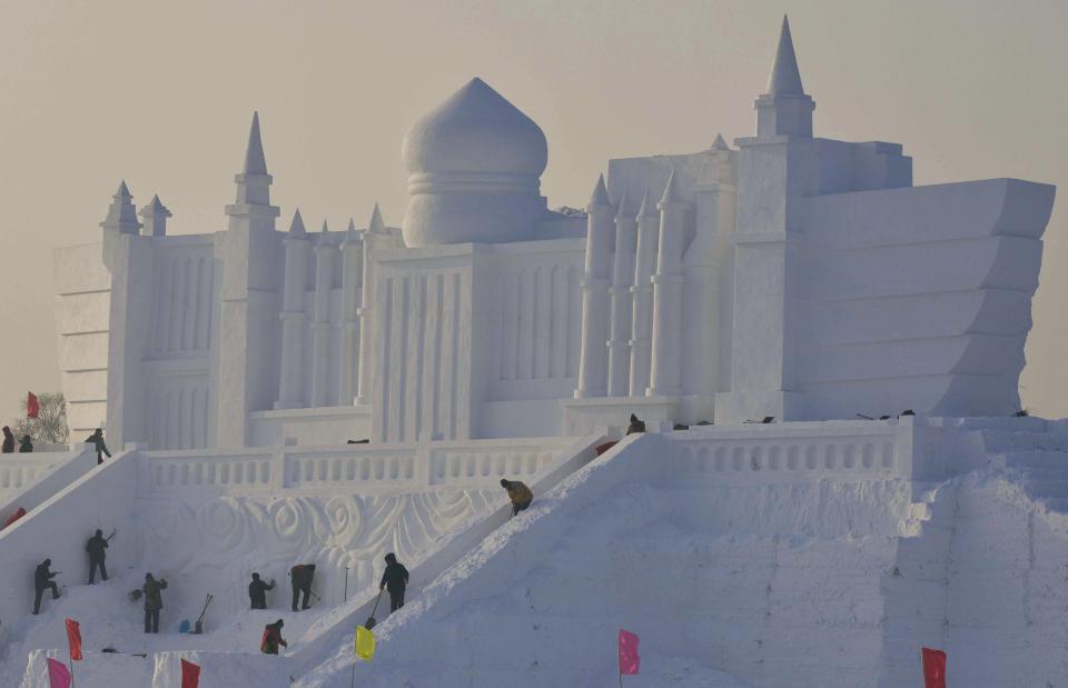 Workers polish a giant snow sculpture ahead of the 30th Harbin Ice and Snow Festival in Harbin