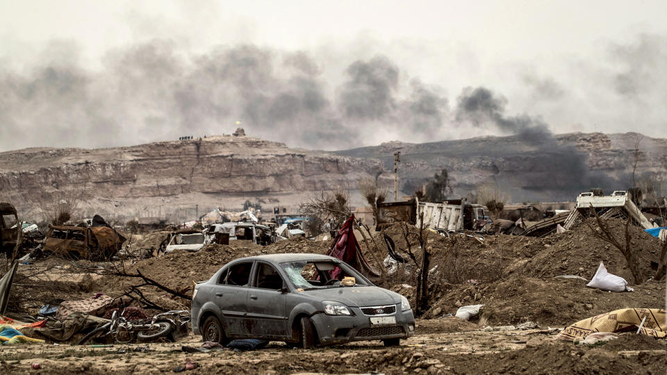 Smoke rising behind destroyed vehicles and damaged buildings in the village of Baghouz in Syria's eastern Deir Ezzor province near the Iraqi border, a day after the Islamic State group's 